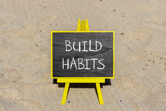 Build habits symbol. Concept word Build habits on beautiful black blackboard. Beautiful sand beach background. Black blackboard. Business build habits concept. Copy space. - Powered by Adobe