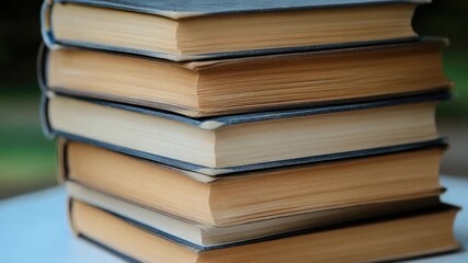 A collection of books stacked on a wooden table, ideal for use in educational or literary settings