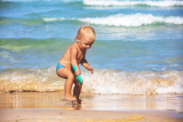 Happy baby playing on the beach on a sunny summer day
