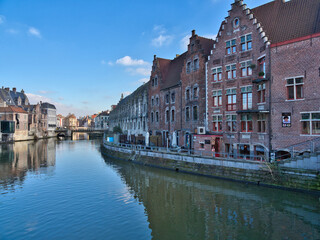 Gent canal and historic center in Ghent, Belgium - Scenic view of the Leie River with historic guild houses and canal tour boats on a sunny day in Ghent, Flanders, Belgium.