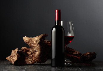 Red wine and old weathered snag on a black stone table.