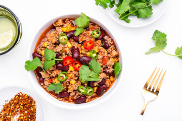 Mexican Chili con carne with beef, beans, corn, cilantro, jalapeno and tomato, white table background, top view