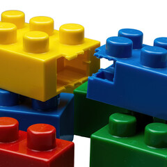 Macro of reflective, colorful plastic toy blocks on gray, yellow block pulling from blue, sharp focus on intricate studs, studio light. Concept of precision and tactility