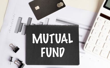 Black card with words mutual fund on financial documents with credit card, calculator and office supplies