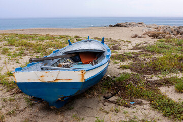 An abandoned old fishing boat on the beach at Roccella Ionica, Calabria, southern Italy