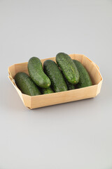 Cucumbers in a wooden box on a grey background. 
