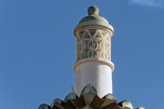 Ornate chimney with decorative top structure Terracotta roof tiles below in Portimao, algarve, Portugal