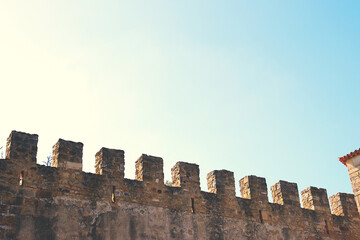 Stone walls of an old castle with battlements at the top