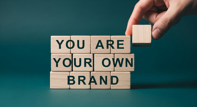 Wooden blocks spelling "You are your own brand",  a hand placing the final block.  Represents personal branding and self-marketing concepts
