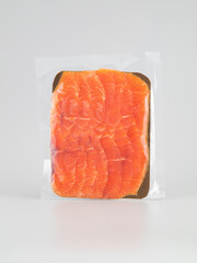 Sliced raw salmon fillet in plastic bag on white background.