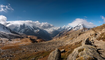 Vast Expanses Of Rugged Terrain And Rocky Outcrops Provide A Stunning Backdrop For Towering Mountains Under Broad Clouds Snow Can Be Seen In The Distance Enhancing The Natural Beauty