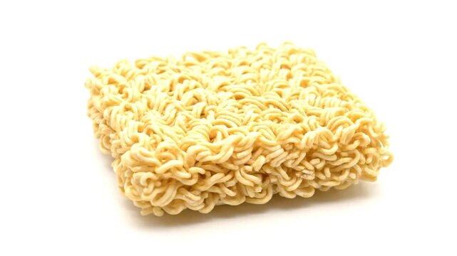 A rectangular block of dried instant noodles with a dense wavy pattern on a stark white backdrop