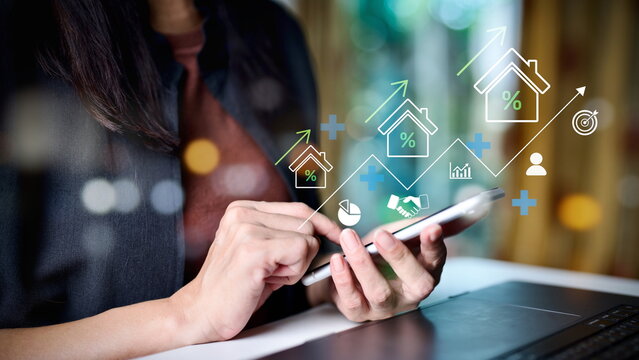 Businesswoman using smartphone with real estate investment icons, symbol of property growth, mortgage, housing loan, financial planning, interest rate, digital economy, and successful home ownership.