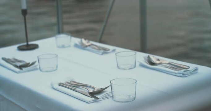 Elegant table set inside transparent glass cabin with white tablecloth