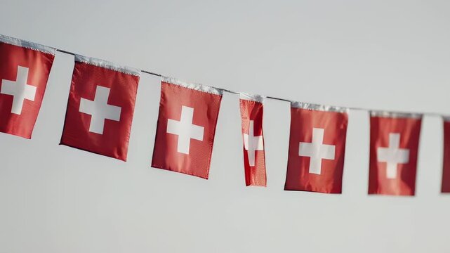 Swiss flags strung on a line against a light gray background