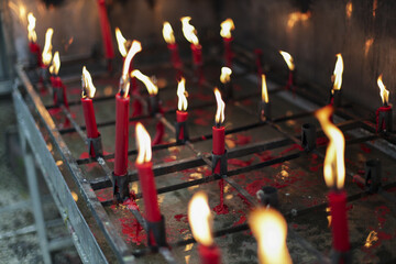 Numerous red candles burn brightly, their dancing flames creating spiritual light within temple....