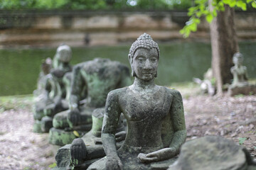 Obraz premium Ancient Buddha statue, an old spiritual sculpture of stone, sits serenely in meditation. Moss covers figure, reflecting calm wisdom and an enduring historical tradition
