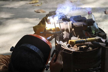Professional welder concentrates on metal, producing bright welding sparks with fiery glow