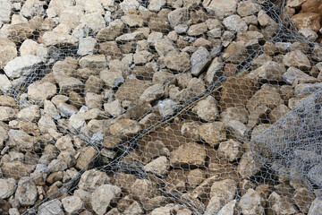 Rough rock and stone gabion mesh wire construction provides stability and protection