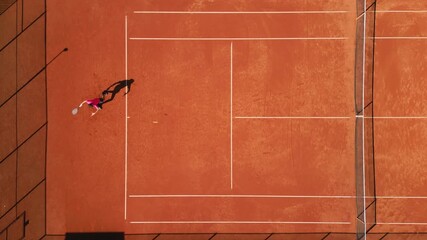 Tennis player in pink outfit practices on clay court, dynamic movement captured aerially. Emphasizes sports training, athleticism, and skill development in a professional setting. - Powered by Adobe