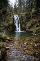 Obraz premium Waterfall cascading into a tranquil pool, surrounded by lush forest