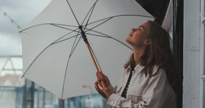 Beautiful young woman outdoors opening umbrella and smiling
