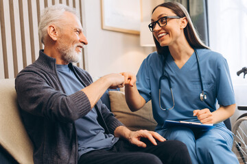 Obraz premium Nurse and senior man giving fist bump at home