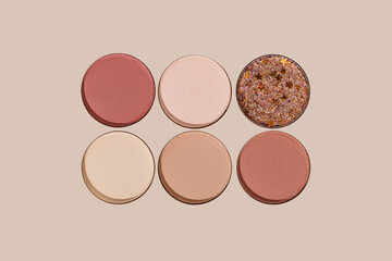 Top view of glitter and matte eyeshadow refills, beige, brown, red, pink, purple colored shades on beige background. Minimal style photo Swatches Eyeshade makeup for cosmetic, beauty concept