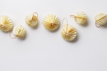 New Year decorative ornaments, golden Christmas flashlights shape bauble on light beige background, Minimal layout with paper festive decor beige balls, modern decor, top view, light effects