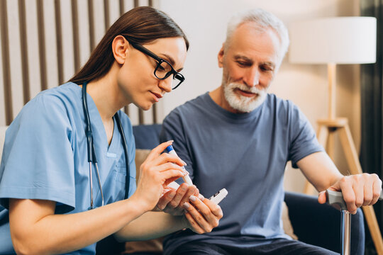 Nurse checking senior man's blood sugar level at home