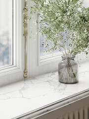 Glass vase with green branches placed on bright window sill.