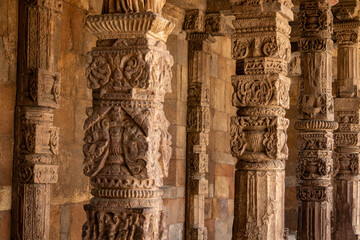 Intricately carved ancient stone pillars with elaborate motifs inside the Qutub Minar complex, Delhi, India, showcasing skilled craftsmanship and rich heritage architecture.