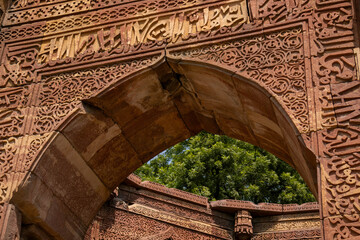 Intricately carved sandstone arch with Arabic calligraphy, part of the Qutub Minar complex in Delhi, India, exemplifying Indo-Islamic heritage architecture and fine stone craftsmanship.