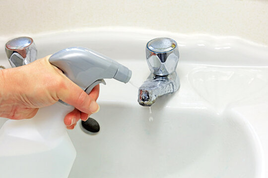woman using a limescale removal solution on a chrome tap