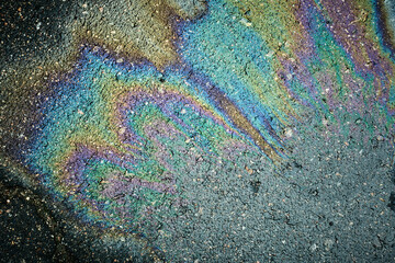 Oil slick on asphalt creating a colorful psychedelic rainbow pattern of iridescent sheen.
