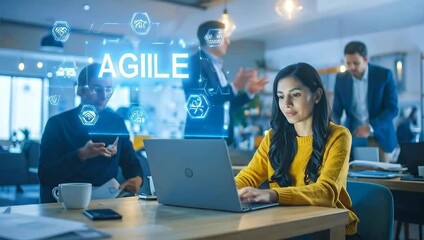 Professionals in a modern office; a woman in the foreground uses a laptop with a holographic AGILE business process display. - Powered by Adobe