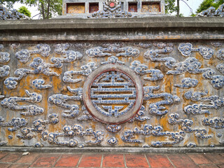 Detailed ceramic wall with intricate Asian motifs - Close-up shot of a textured wall with ornate blue and white porcelain tiles and a central circular relief.