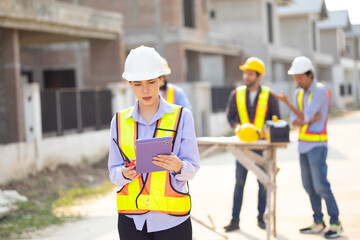 Tablet computer Caucasian female engineer use walkie talkie transmitter, radio : Architect, contractor and architecture standing at house building under construction site. safety harthat helmet