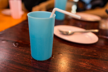 A blue plastic glass for cool drink on a restaurant table. Ice water in plastic cup