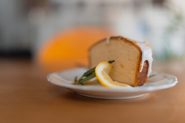 Delicate lemon drizzle cake slice, soft and fluffy, with a tangy lemon glaze and a sprig of mint.