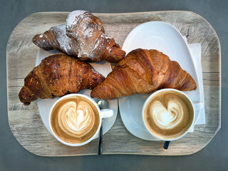 fresh baked croissant and cup of coffee on a tray