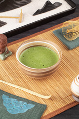 Matcha green tea in a bowl and Japanese accessories on bamboo mat.