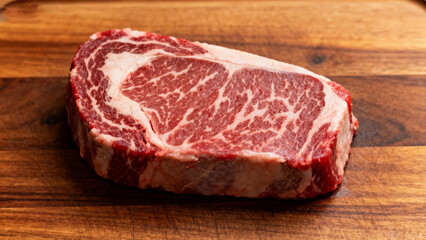 Obraz premium Raw ribeye steak on wooden board