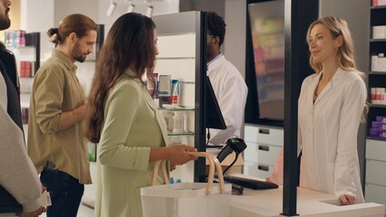 Fototapeta premium Multiracial woman man pharmacy consultants professional healthcare workers pharmacists drugstore indoors serving customers people medicine buying pills vitamins at cashier counter health assisting