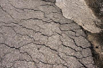Broken tarmac and potholes on the damaged surface of a road. No people.