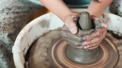 Close up of female hands crafting clay on spinning pottery wheel, selective focus. Workshop training in traditional ceramic art, handmade design, cultural craft, shaping process, artisan skill.
