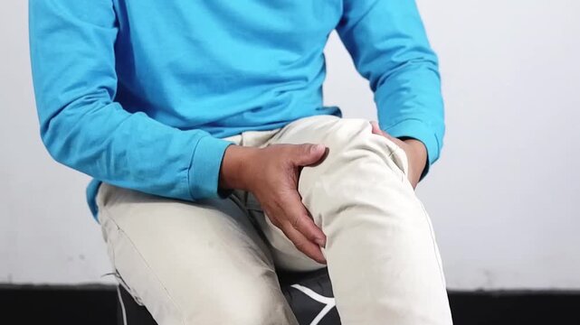 Man with knee pain, A young man massages his knee due to knee pain and muscle aches caused by Runner's Knee or Patellofemoral Pain Syndrome, osteoarthritis, arthritis, rheumatism, and Patellar Tendini