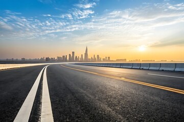 Fototapeta premium Empty asphalt highway stretches towards city skyline and sunset over water