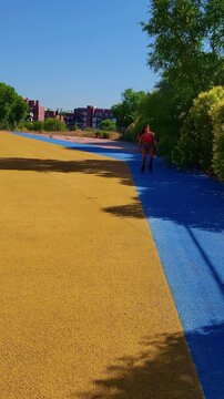 Athletic woman enjoying a sunny day rollerblading on a blue and yellow path in a public park