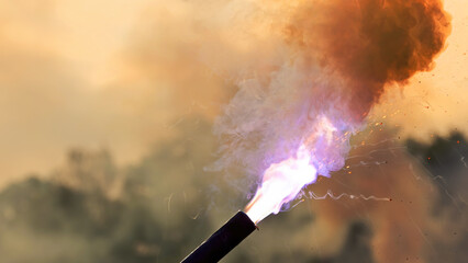 Burning Bengal torch emitting smoke, fire, and bright sparks against dark background.